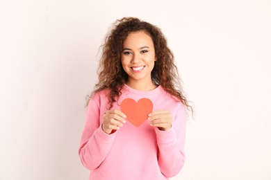 Photo of African-American woman with paper heart on white background