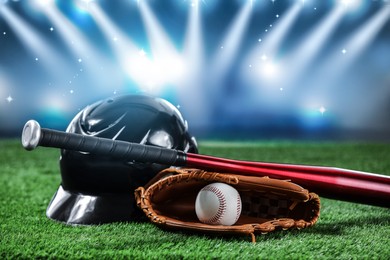 Baseball bat, glove, helmet and ball on grass at stadium