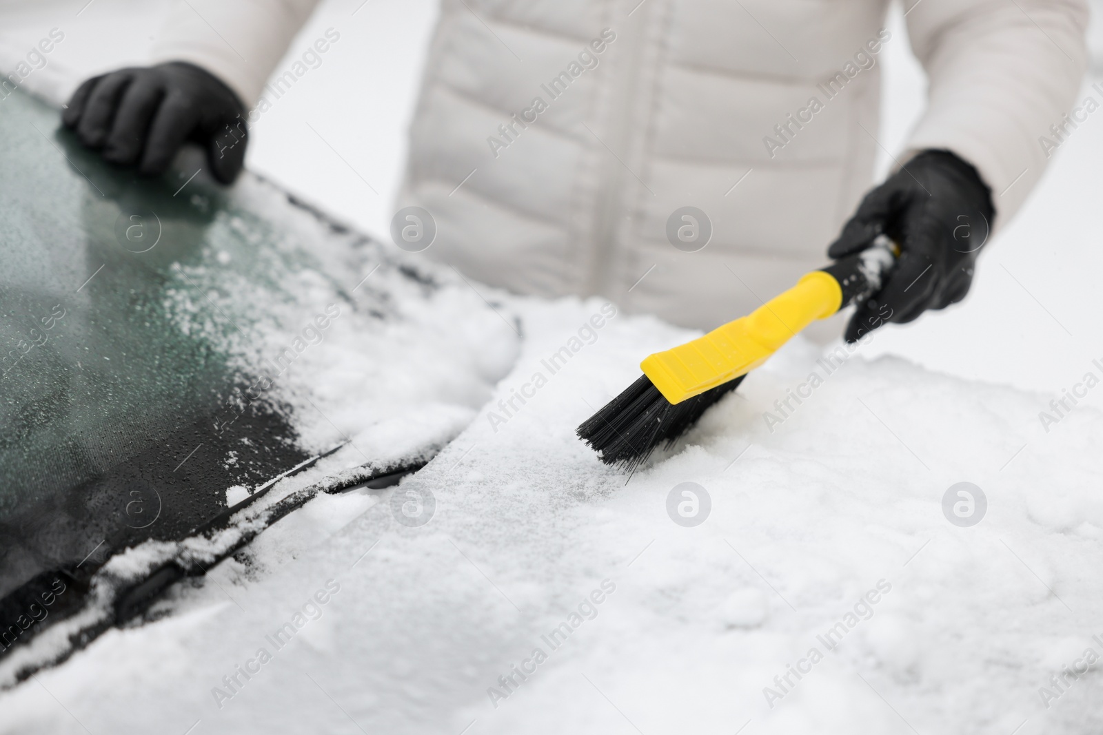 Photo of Man cleaning snow from car hood outdoors, closeup