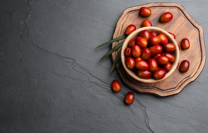 Palm oil fruits in bowl on black table, flat lay. Space for text