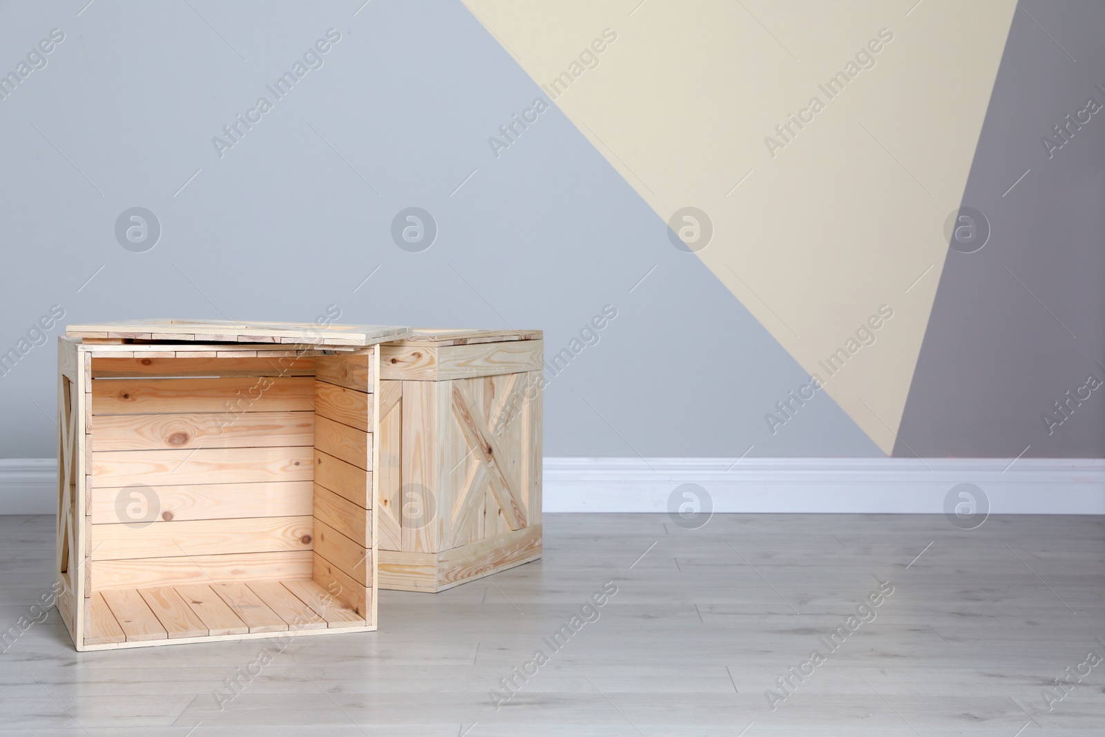 Photo of Wooden crates on floor at color wall. Space for text