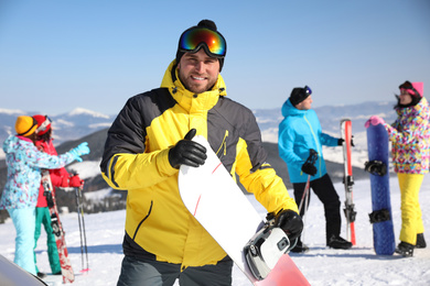Photo of Young man with snowboard at ski resort. Winter vacation