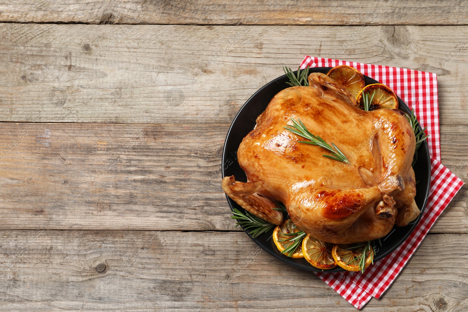 Photo of Tasty roasted chicken with rosemary and lemon on wooden table, top view. Space for text