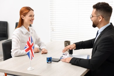 Photo of Embassy worker approving immigration application to United Kingdom to smiling woman in office