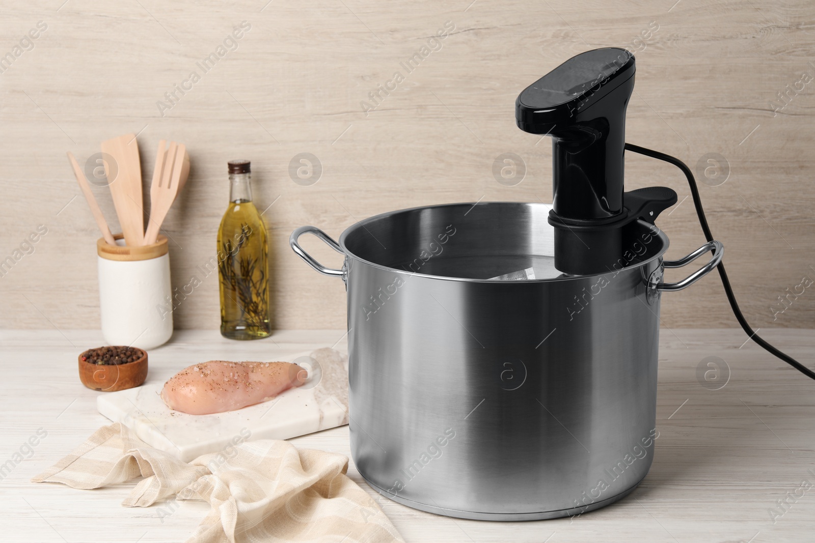 Photo of Thermal immersion circulator in pot and meat on white wooden table. Sous vide cooking