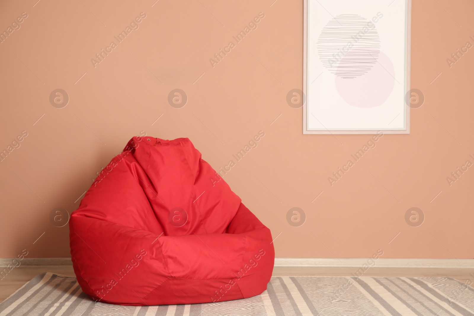 Photo of Red bean bag chair on floor near beige wall indoors