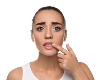 Photo of Emotional woman with herpes touching lips on white background