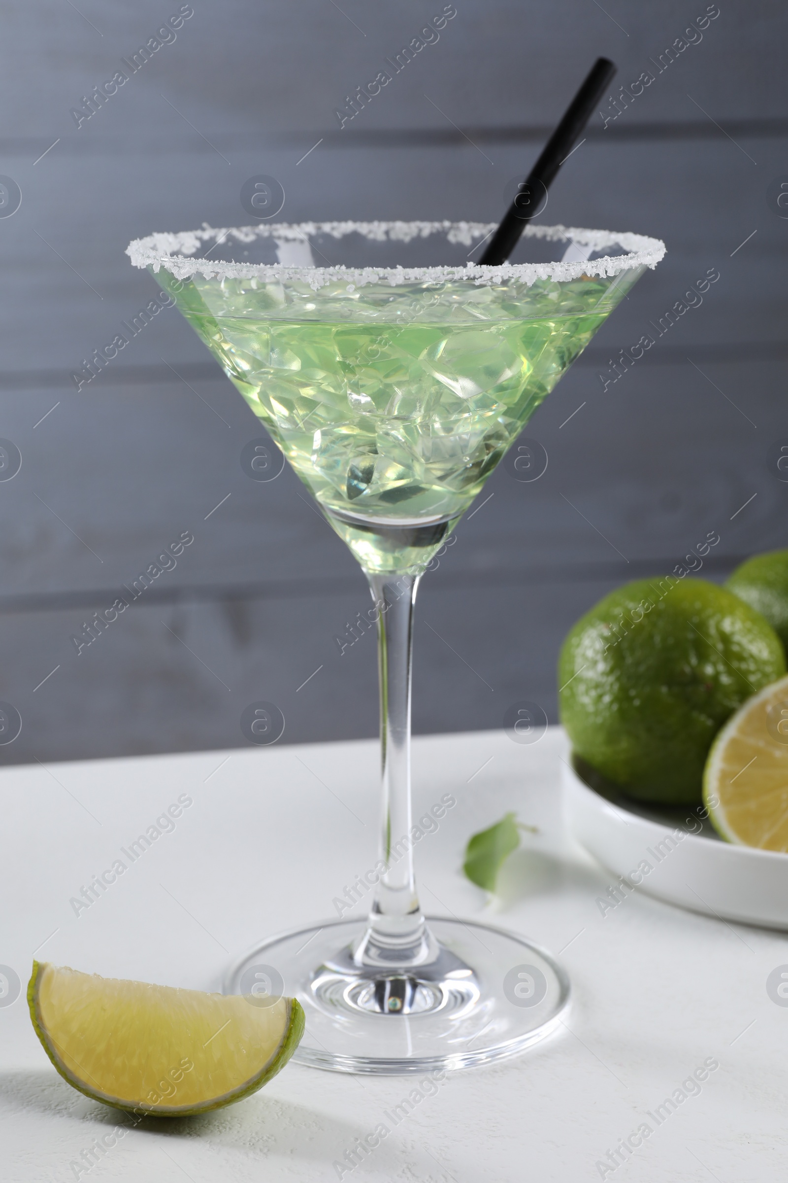 Photo of Delicious Margarita cocktail with ice cubes in glass and lime on white table