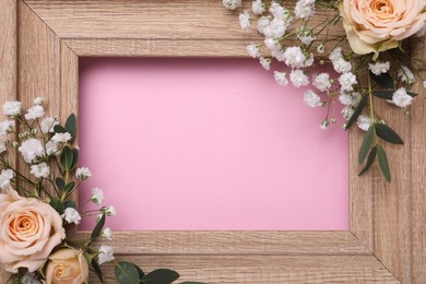 Photo of Wooden frame with gypsophila flowers, eucalyptus and roses on pink background, closeup. Space for text