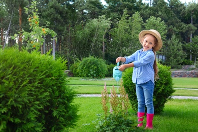 Photo of Little girl watering flowers in backyard. Home gardening