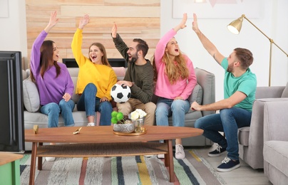 Photo of Group of friends celebrating victory of favorite soccer team in living room