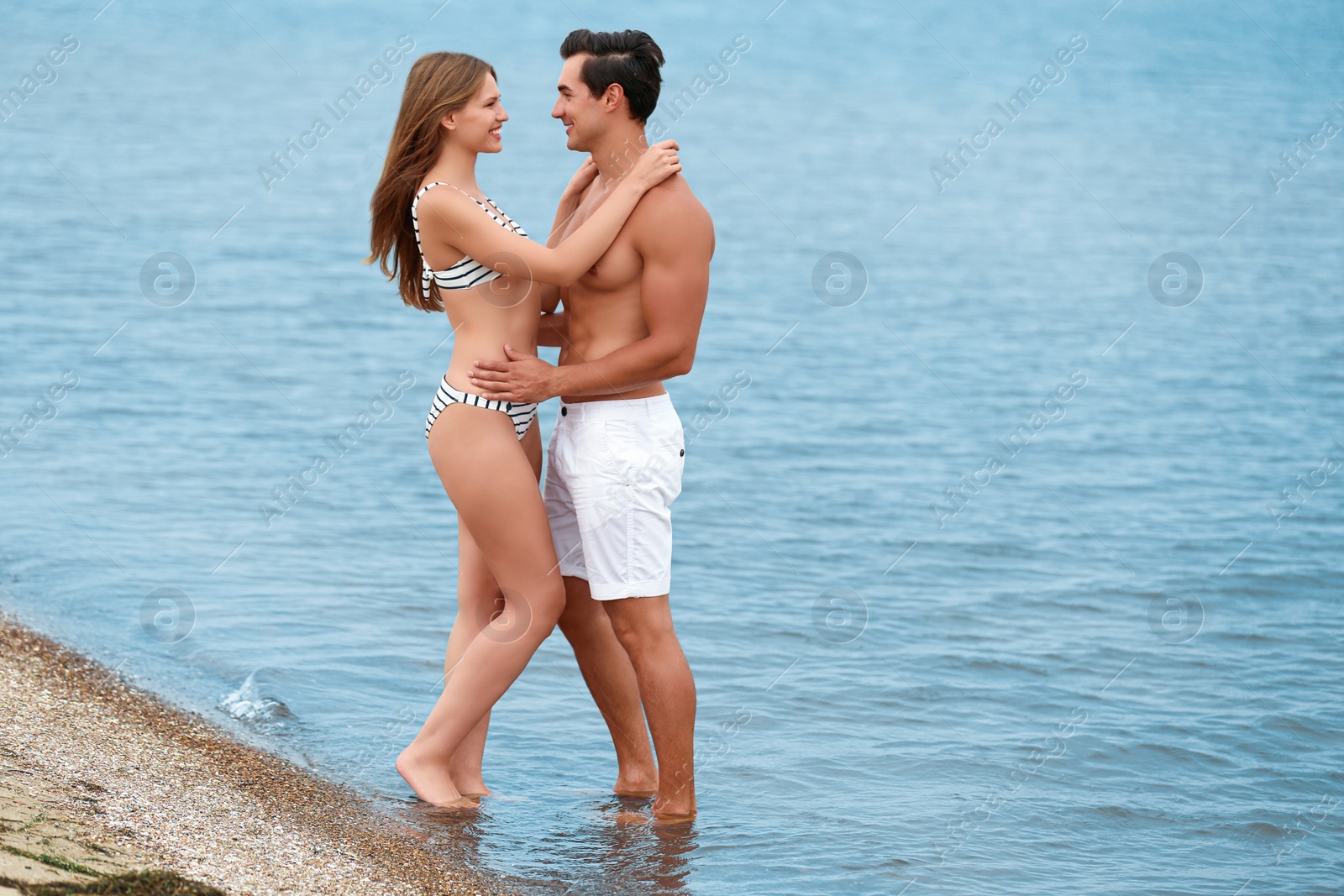 Photo of Happy young couple spending time together on sea beach. Space for text