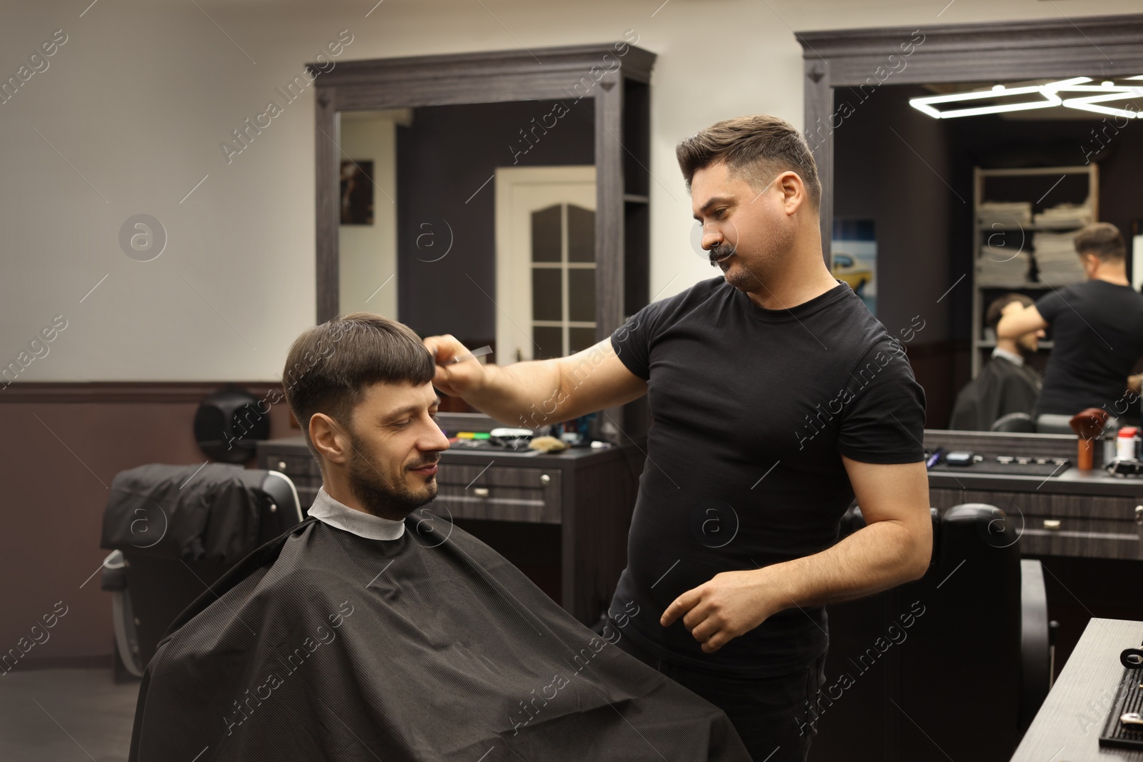 Photo of Professional hairdresser making stylish haircut in barbershop