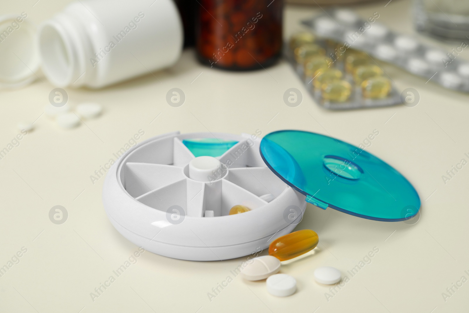 Photo of Plastic pill box and different medicaments on white table, closeup