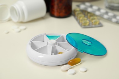 Plastic pill box and different medicaments on white table, closeup