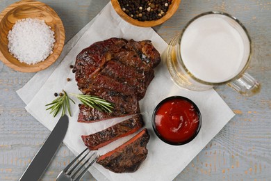 Photo of Mug with beer, fried steak and sauce on grey wooden table, flat lay