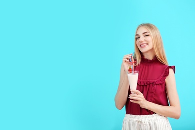 Photo of Young woman with glass of delicious milk shake on color background