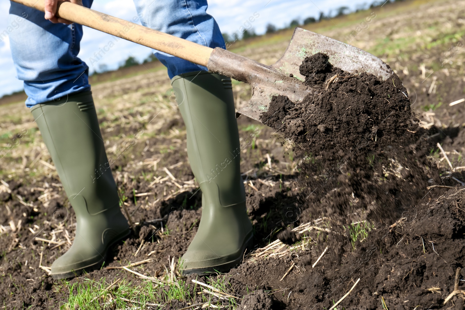 Photo of Man digging soil with shovel in field, closeup