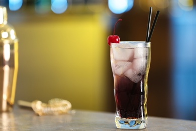 Fresh alcoholic cocktail with cherry on bar counter, space for text
