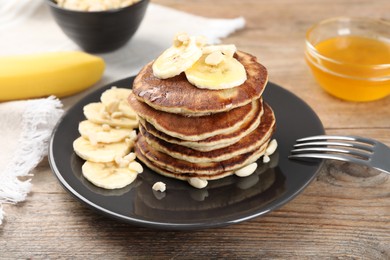 Plate of banana pancakes served on wooden table, closeup