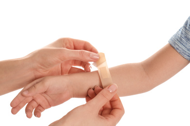 Photo of Mother putting sticking plaster onto son's arm on white background, closeup