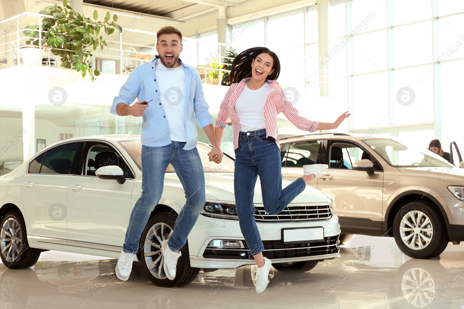 Photo of Happy couple with car key in modern auto dealership