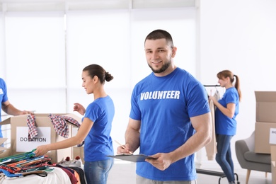 Male volunteer with clipboard listing donations indoors