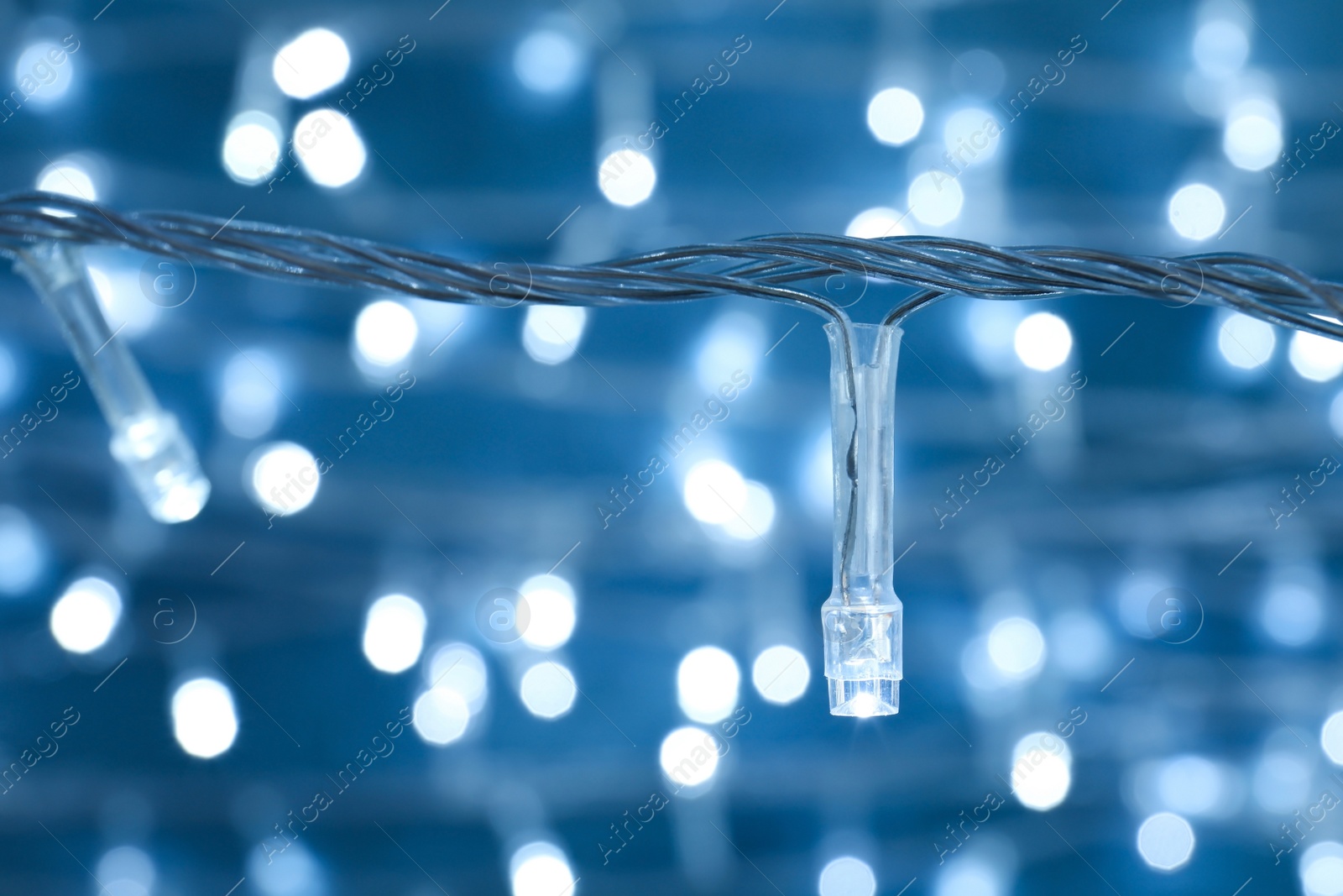 Photo of Beautiful Christmas lights on color background, closeup