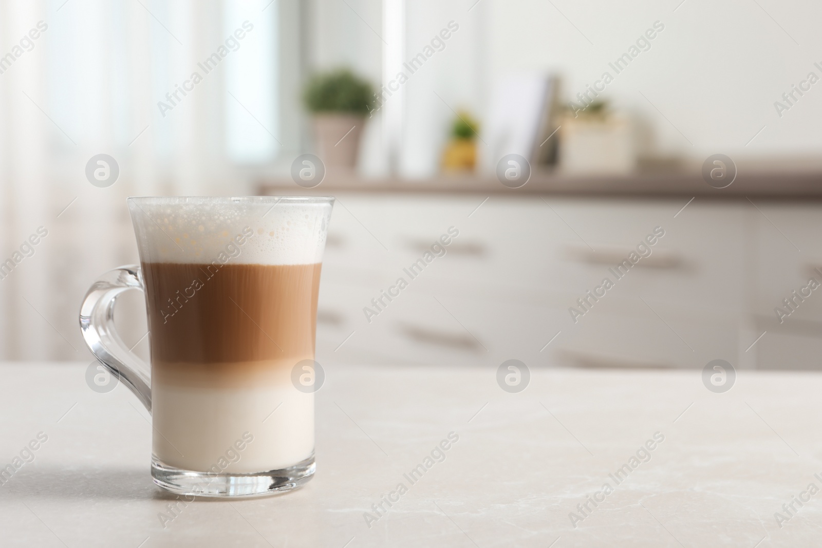 Photo of Glass cup of delicious layered coffee on light marble table indoors, space for text