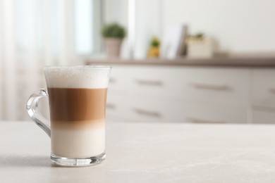 Photo of Glass cup of delicious layered coffee on light marble table indoors, space for text