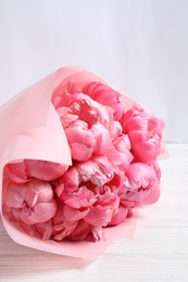 Photo of Bouquet of beautiful pink peonies on white wooden table
