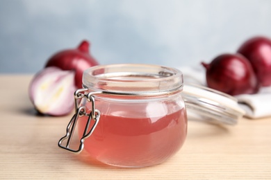 Photo of Glass jar with onion syrup and fresh ingredient on wooden table