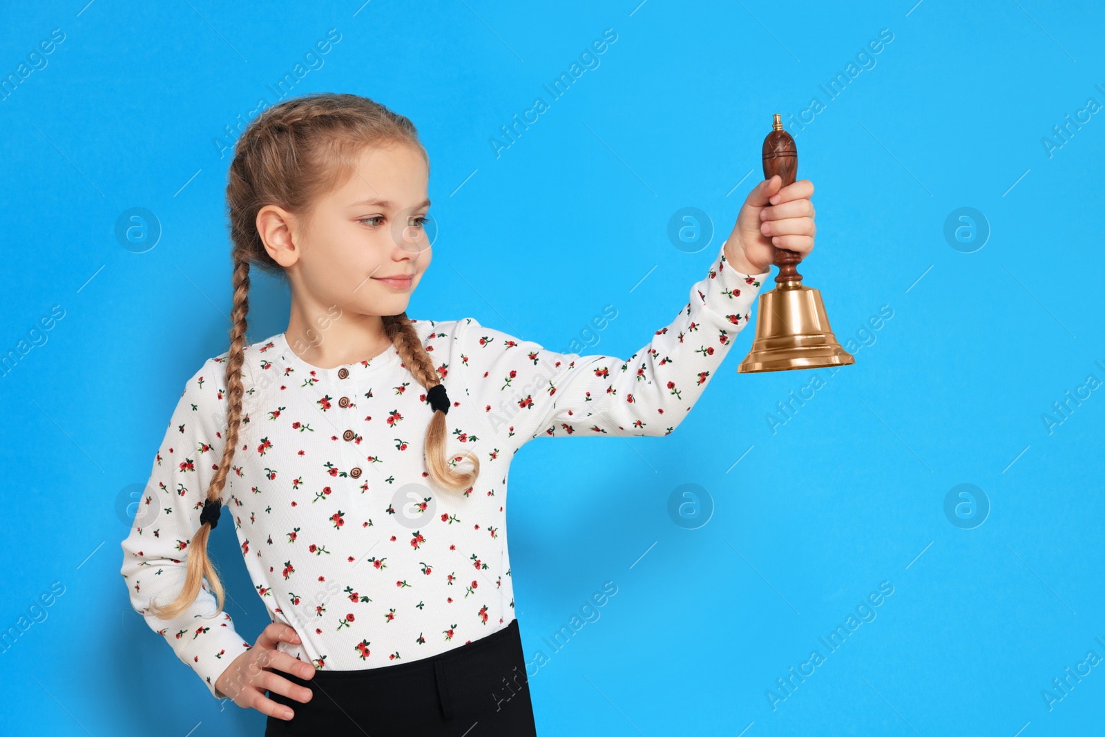 Photo of Pupil with school bell on light blue background