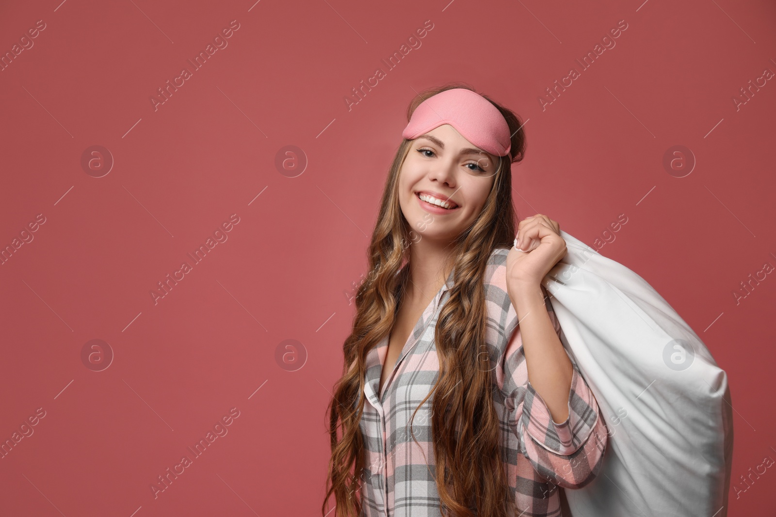 Photo of Beautiful woman with pillow on dusty rose background, space for text. Bedtime