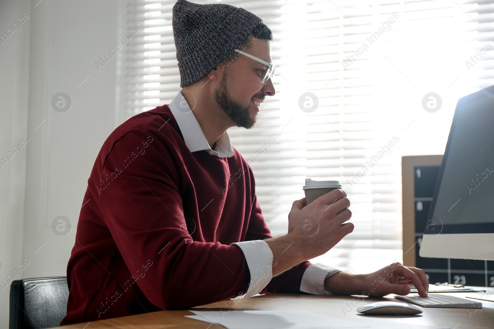 Photo of Freelancer with cup of coffee working on computer at table indoors