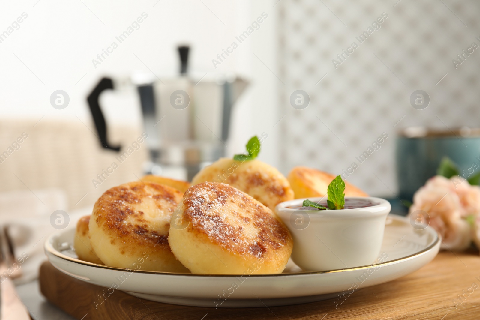 Photo of Delicious cottage cheese pancakes with jam, mint and icing sugar on wooden board