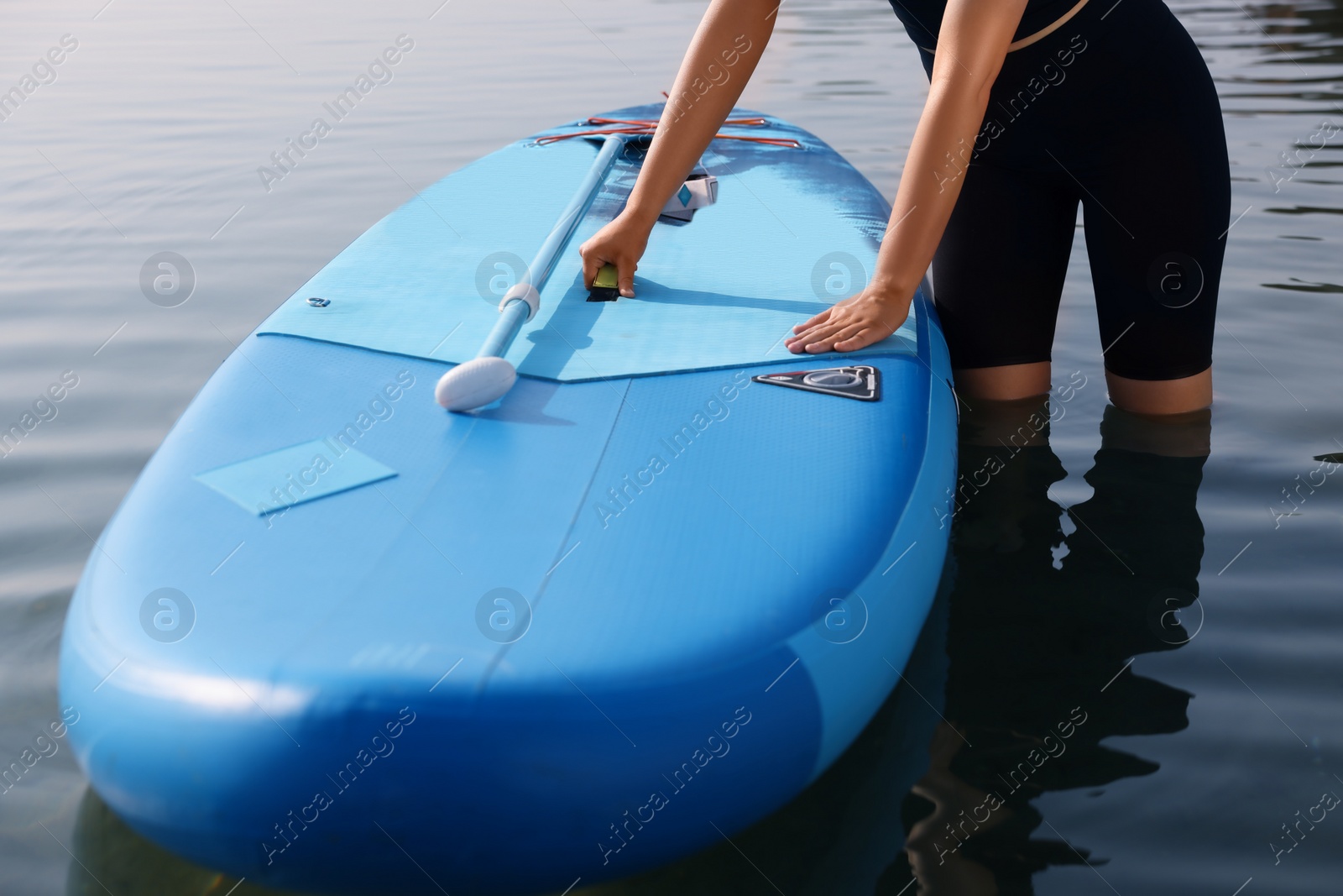 Photo of Woman standing near SUP board in water, closeup