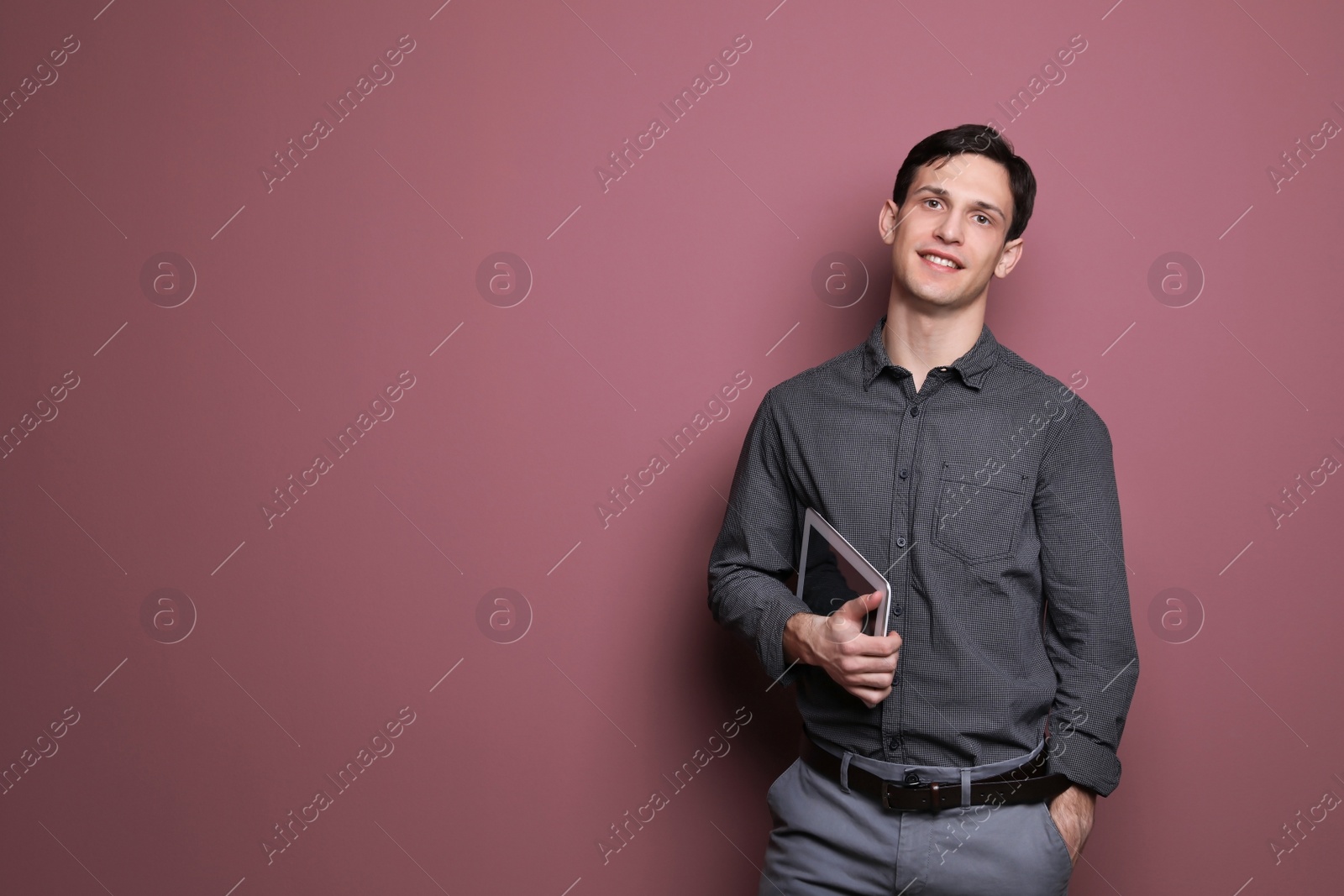 Photo of Portrait of confident young man with tablet on color background