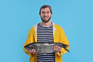 Photo of Fisherman with caught fish on light blue background