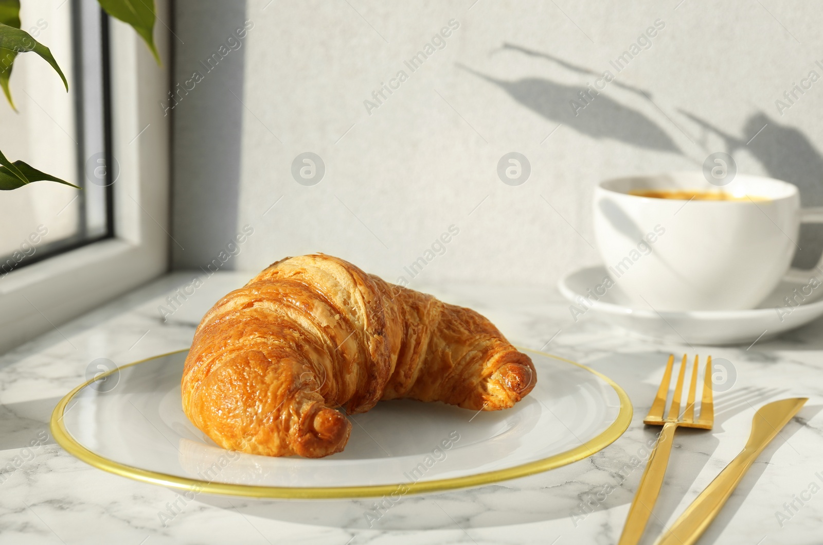 Photo of Delicious fresh croissant served with coffee on white marble table, closeup. Space for text