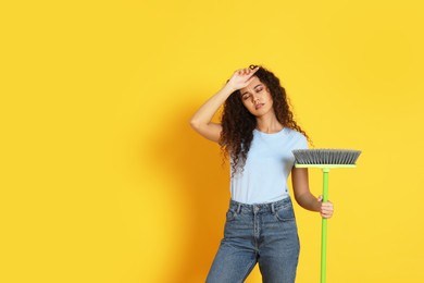 Photo of Tired African American woman with green broom on orange background, space for text