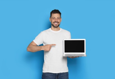 Photo of Happy man holding laptop on light blue background