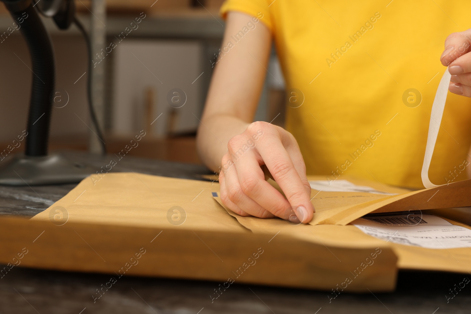 Photo of Post office worker with envelopes at counter indoors, closeup