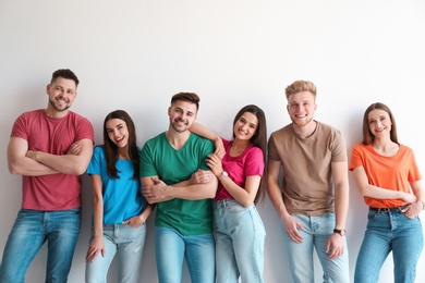 Photo of Group of happy people posing near light wall