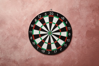 Dart board hanging on pink textured wall