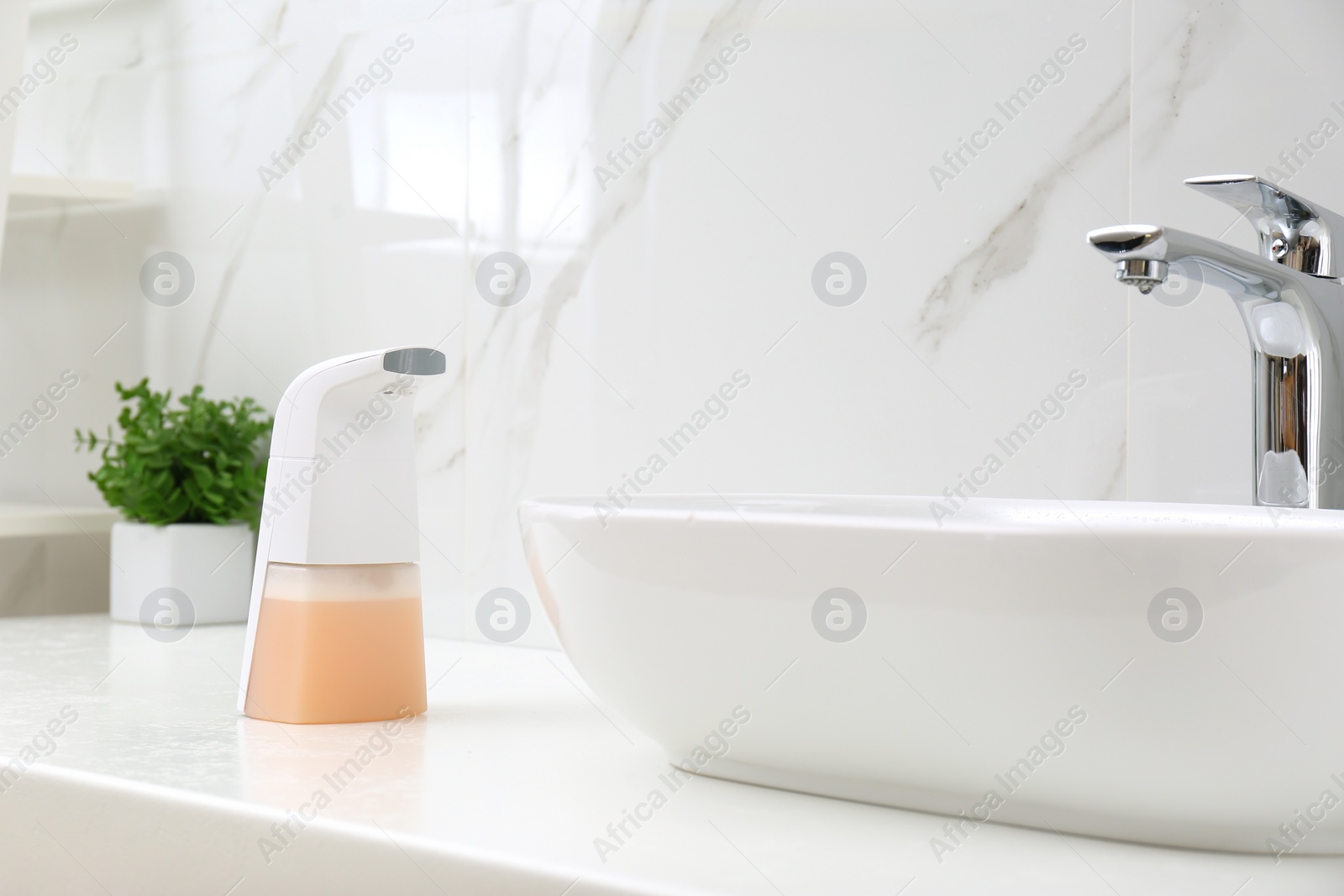 Photo of Modern automatic soap dispenser near sink in bathroom