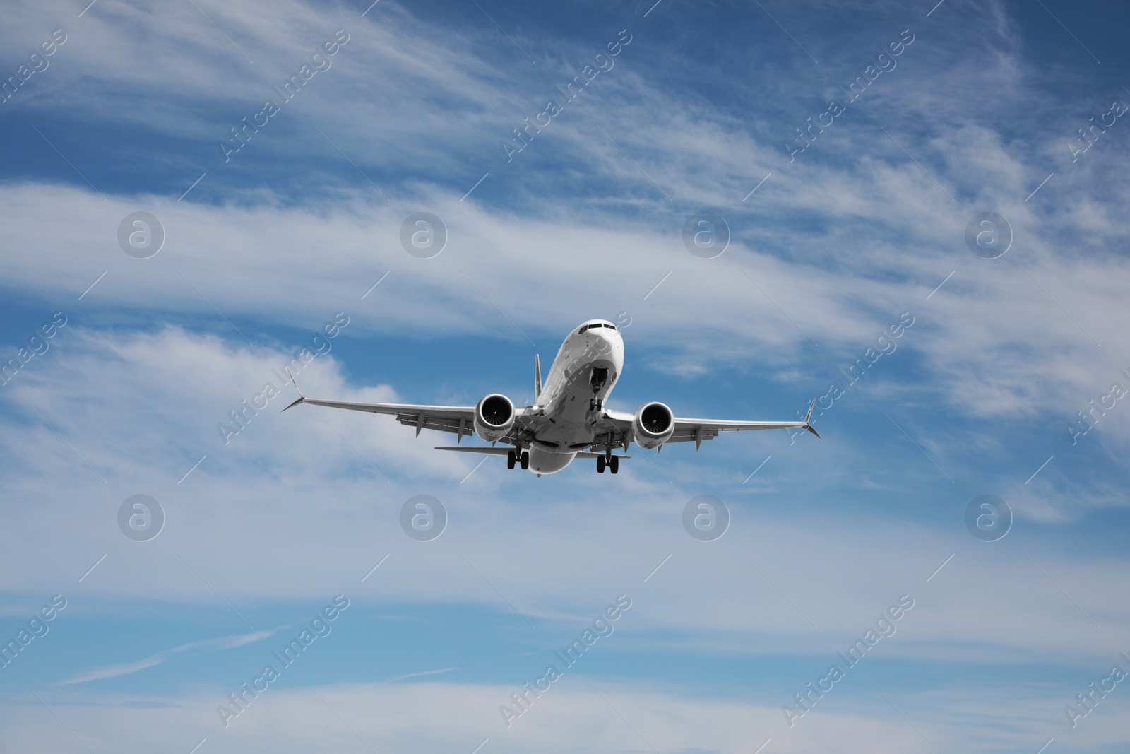 Photo of Modern white airplane flying in cloudy sky