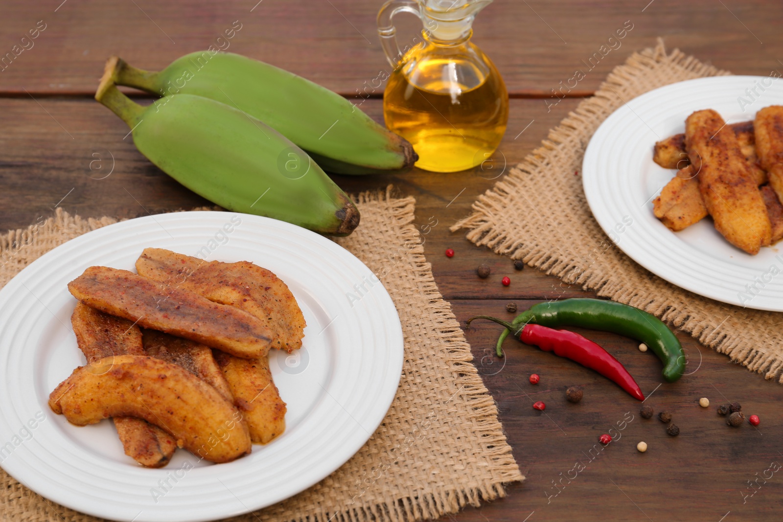 Photo of Delicious fried bananas, fresh fruits and different peppers on wooden table