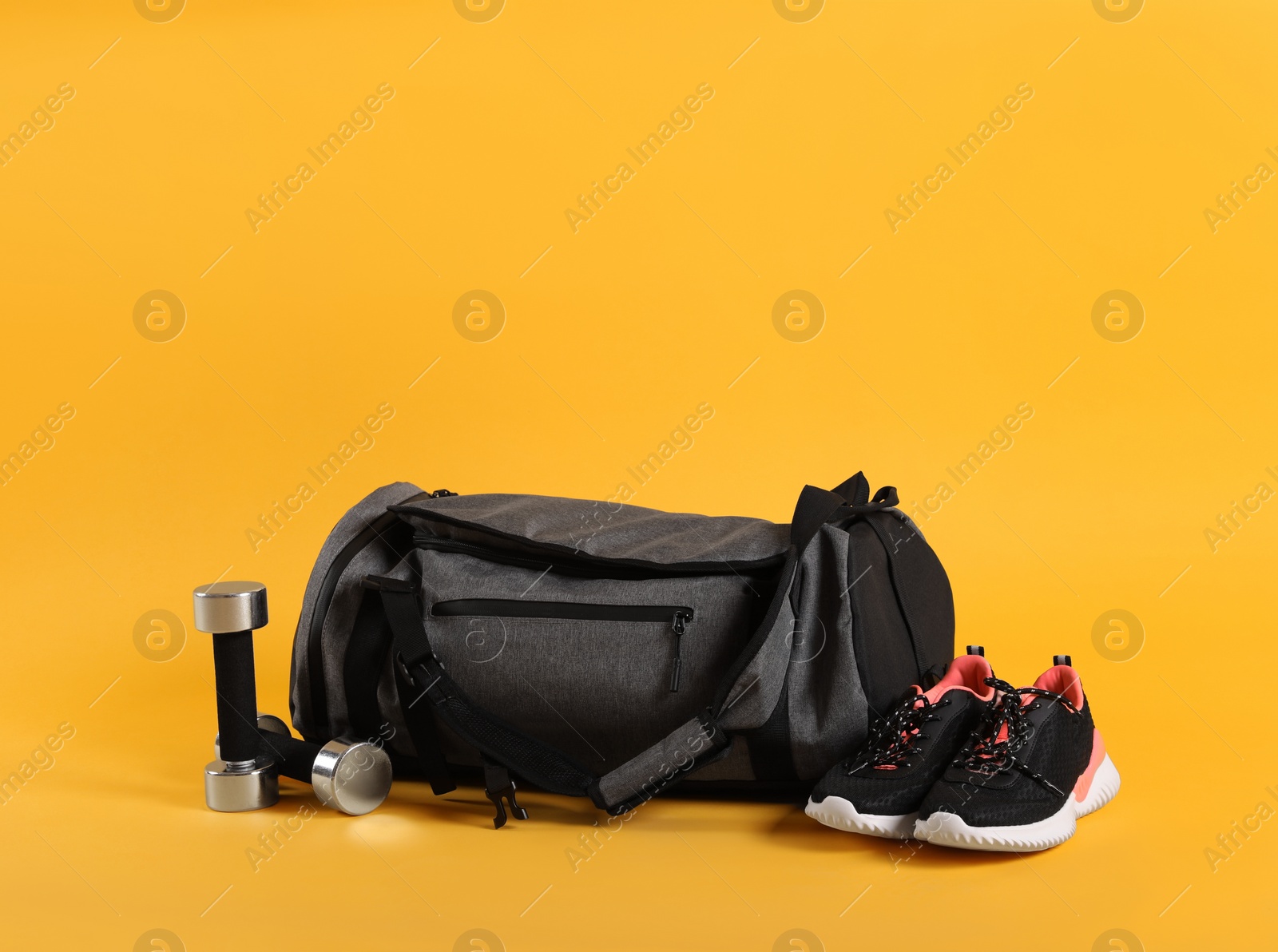 Photo of Sports bag and gym equipment on yellow background