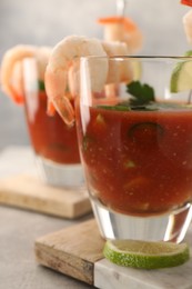 Photo of Tasty shrimp cocktail with sauce in glasses and lime on light grey table, closeup